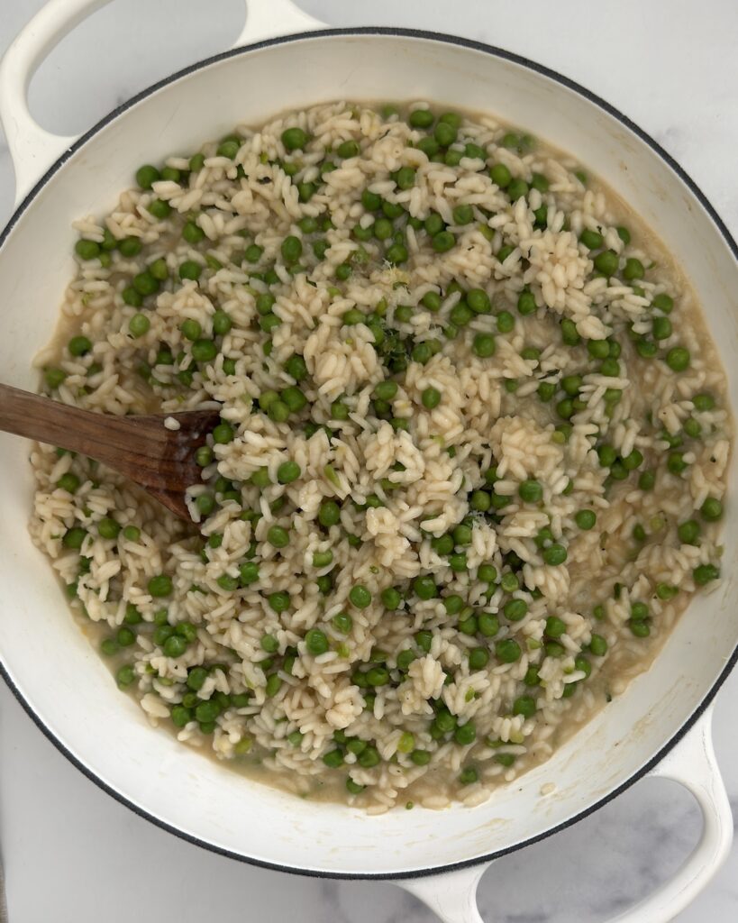 Creamy spring pea risotto with arborio rice and peas cooking in a skillet.