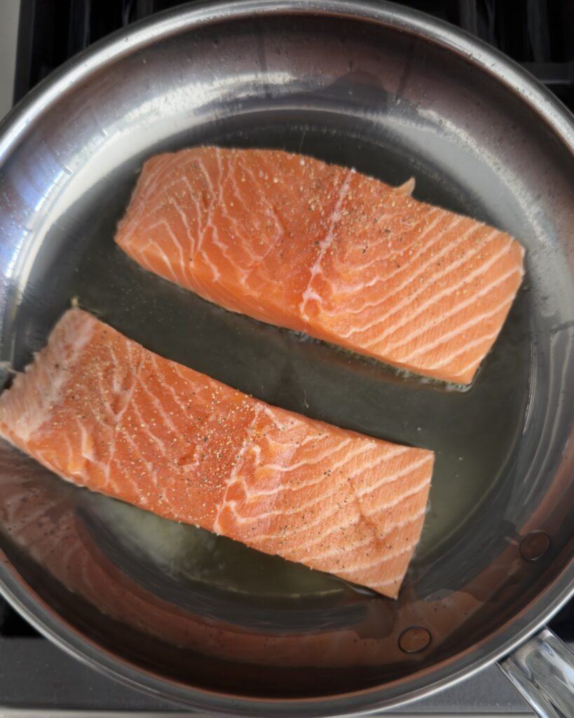salmon fillets cooking skin side down in a skillet for salmon piccata