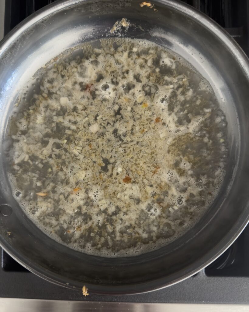 white wine lemon sauce simmering in a skillet with shallots for salmon piccata