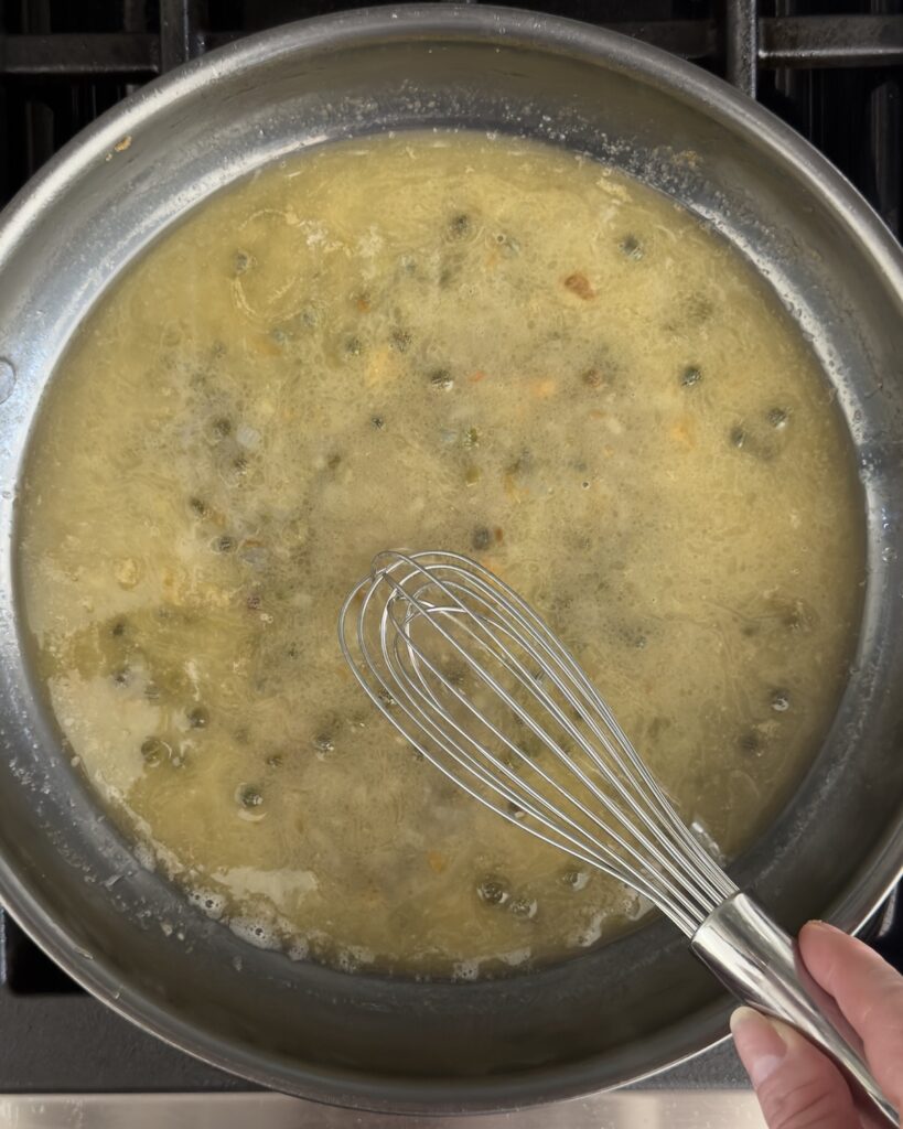 lemon butter caper sauce whisked in a skillet for salmon piccata