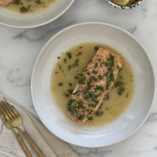 salmon piccata plated with lemon caper sauce and fresh parsley