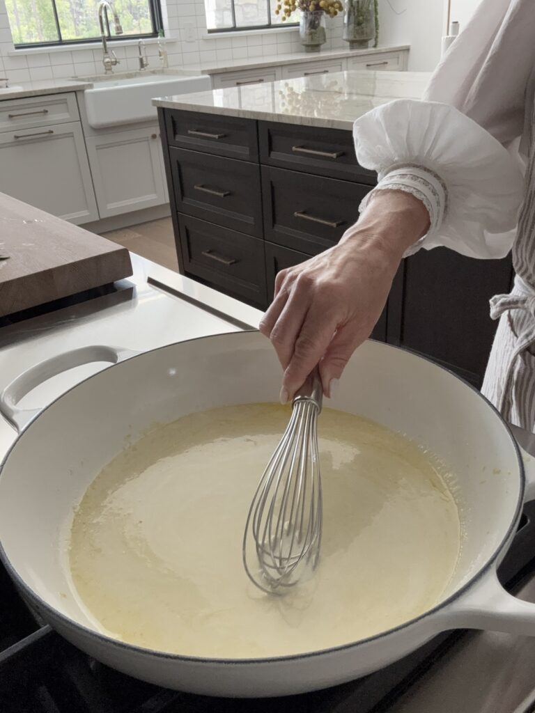 Creamy lemon sauce for spaghetti al limone being whisked in a sauté pan with lemon juice, cream, and butter