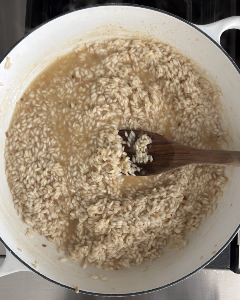 Arborio rice is simmering with vegetable stock while making spring pea risotto.