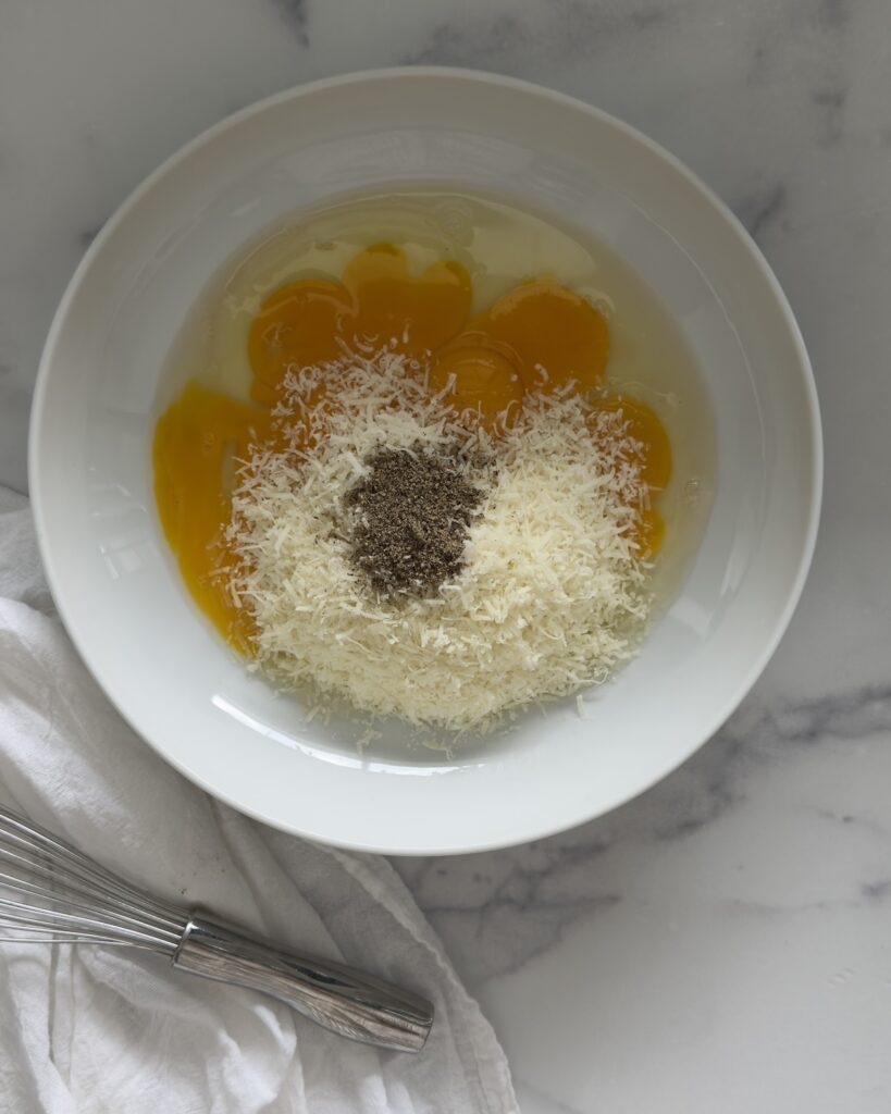 egg yolks, Pecorino Romano cheese, and black pepper in a bowl for making carbonara sauce