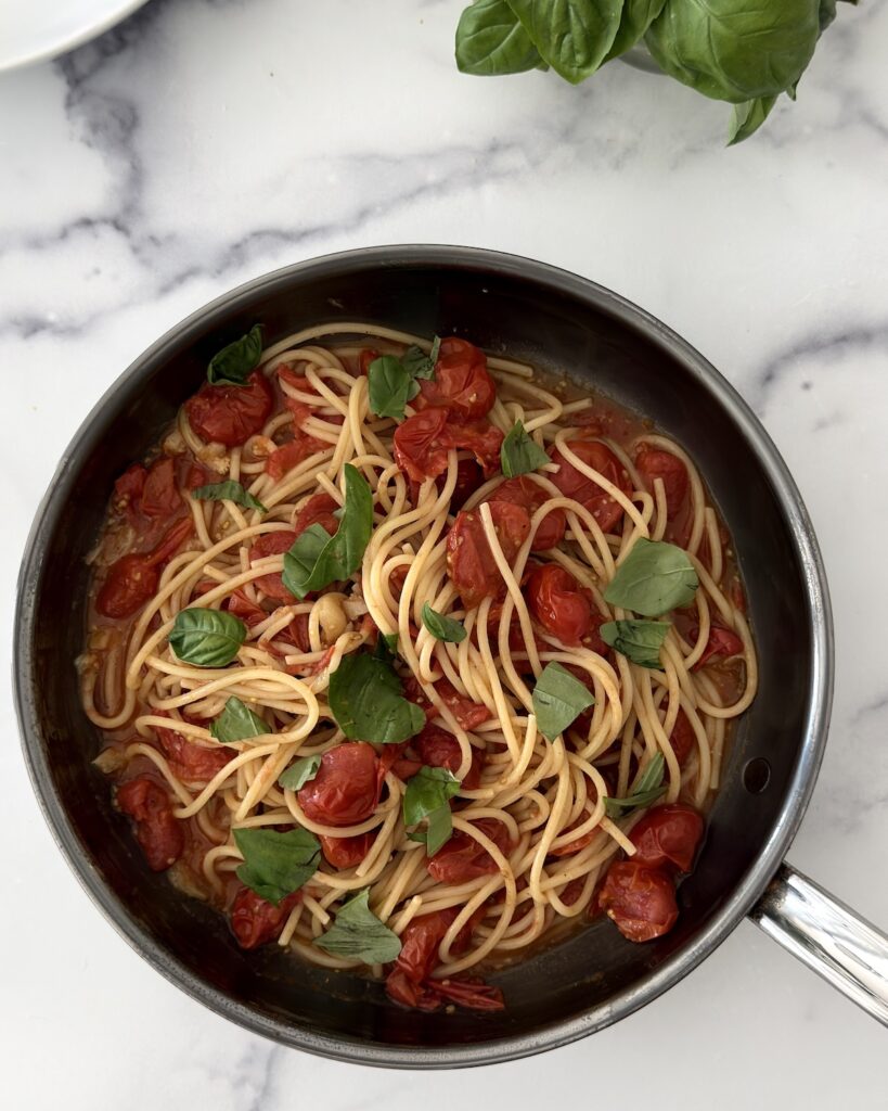 Cherry tomato spaghetti sauce tossed with blistered cherry tomatoes, olive oil, garlic, and fresh basil in a skillet.
