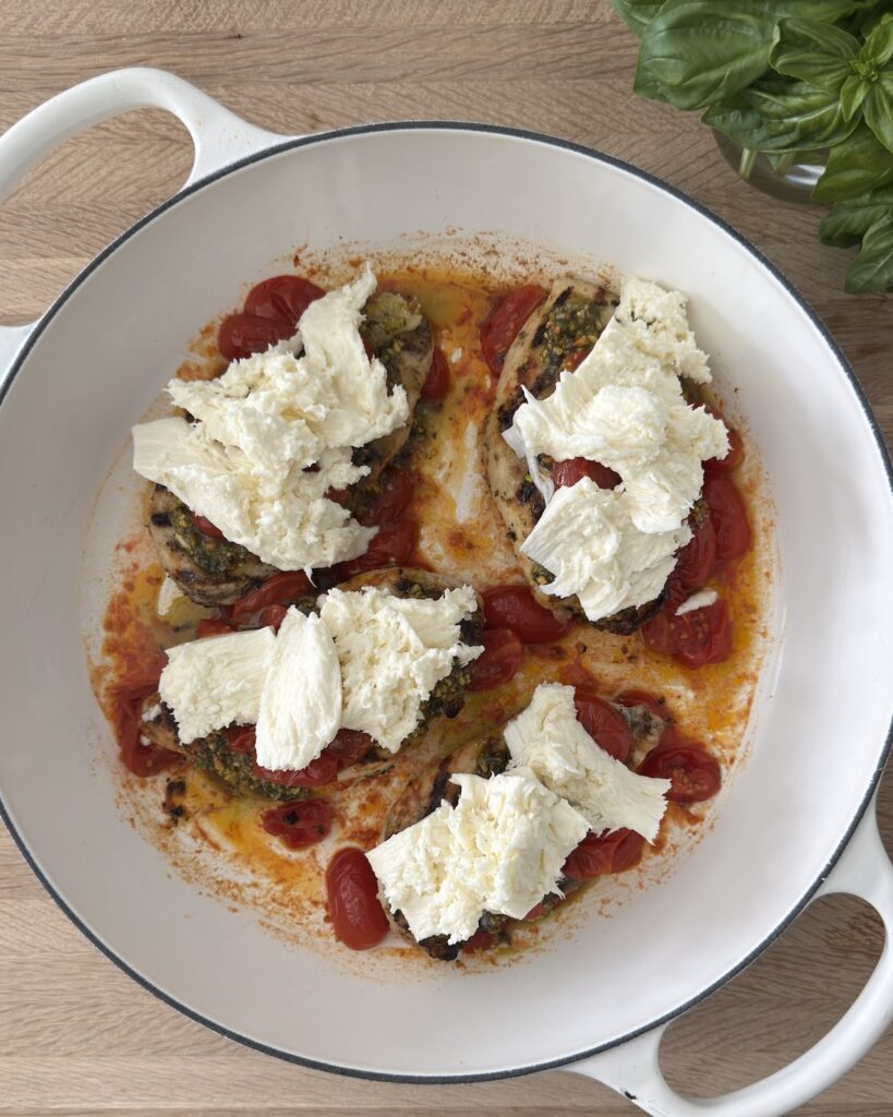 Chicken Margherita with fresh mozzarella and blistered tomatoes before before going into the broiler.