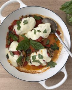 Chicken Margherita with melted mozzarella, blistered tomatoes, fresh basil, and grilled chicken in a white skillet.