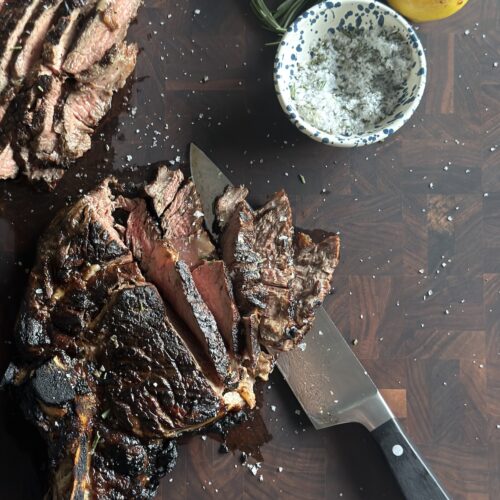 Italian steak (bistecca alla Fiorentina) sliced and served with rosemary sea salt and grilled lemon.