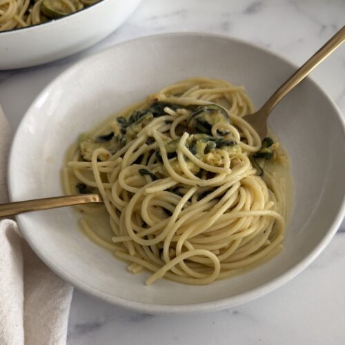 zucchini pasta made with spaghetti, roasted zucchini, garlic-infused olive oil, fresh mint, basil, and Parmesan cheese in a shallow bowl.