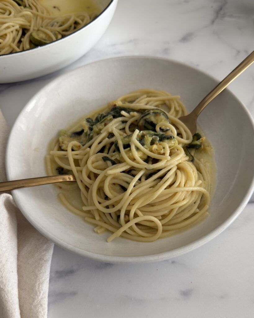 zucchini pasta made with spaghetti, roasted zucchini, garlic-infused olive oil, fresh mint, basil, and Parmesan cheese in a shallow bowl.