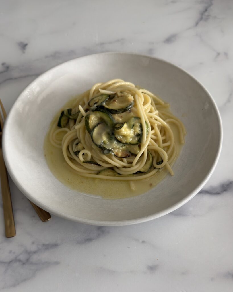 zucchini pasta made with spaghetti, roasted zucchini, garlic-infused olive oil, fresh mint, basil, and Parmesan cheese in a shallow bowl.