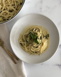 zucchini pasta made with spaghetti, roasted zucchini, garlic-infused olive oil, fresh mint, basil, and Parmesan cheese in a shallow bowl.