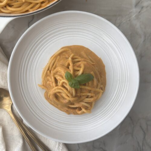 Creamy tomato pasta made with cherry tomatoes, burrata, garlic, and basil served in a white pasta bowl.