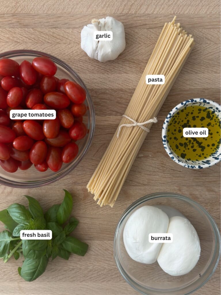 Ingredients for creamy tomato pasta including cherry tomatoes, burrata, pasta, garlic, basil, and olive oil.