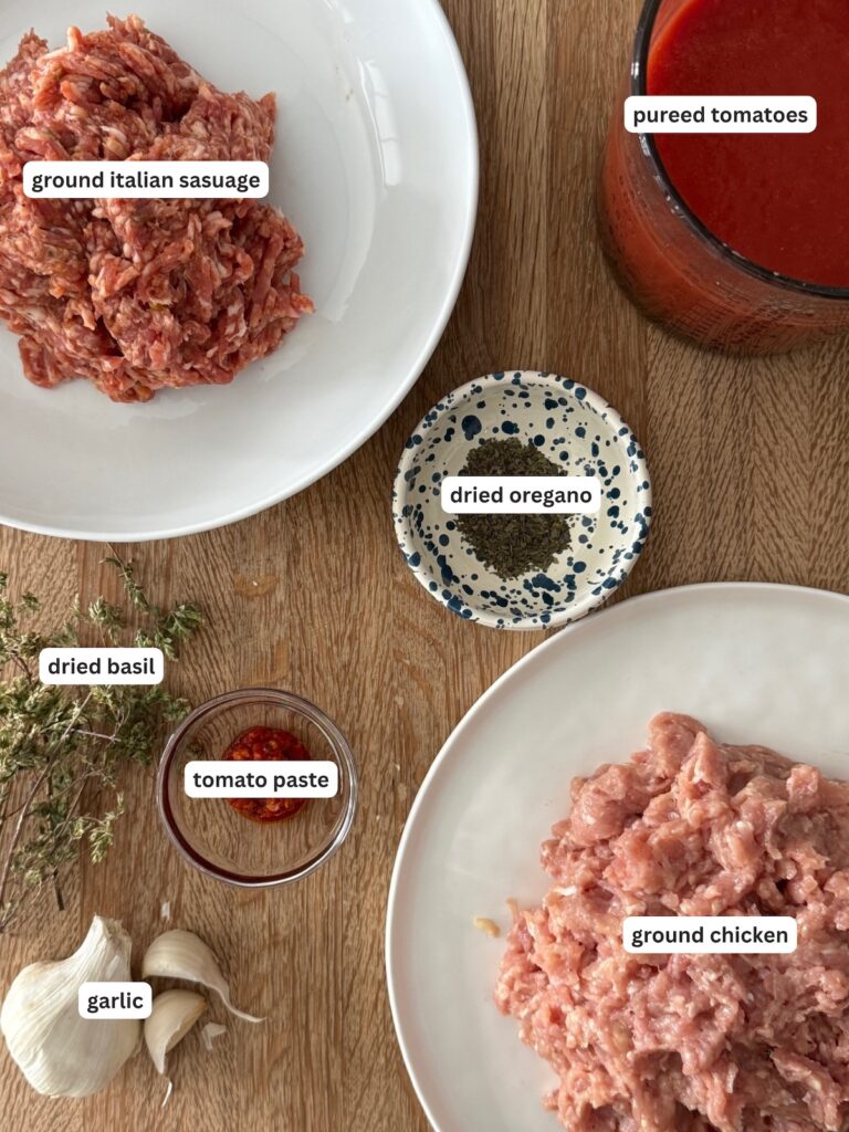 Chicken Bolognese ingredients with ground chicken, Italian sausage, tomato puree, tomato paste, garlic and dried herbs.