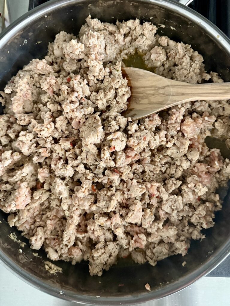 Chicken Bolognese made with ground chicken and Italian sausage browning in a skillet.
