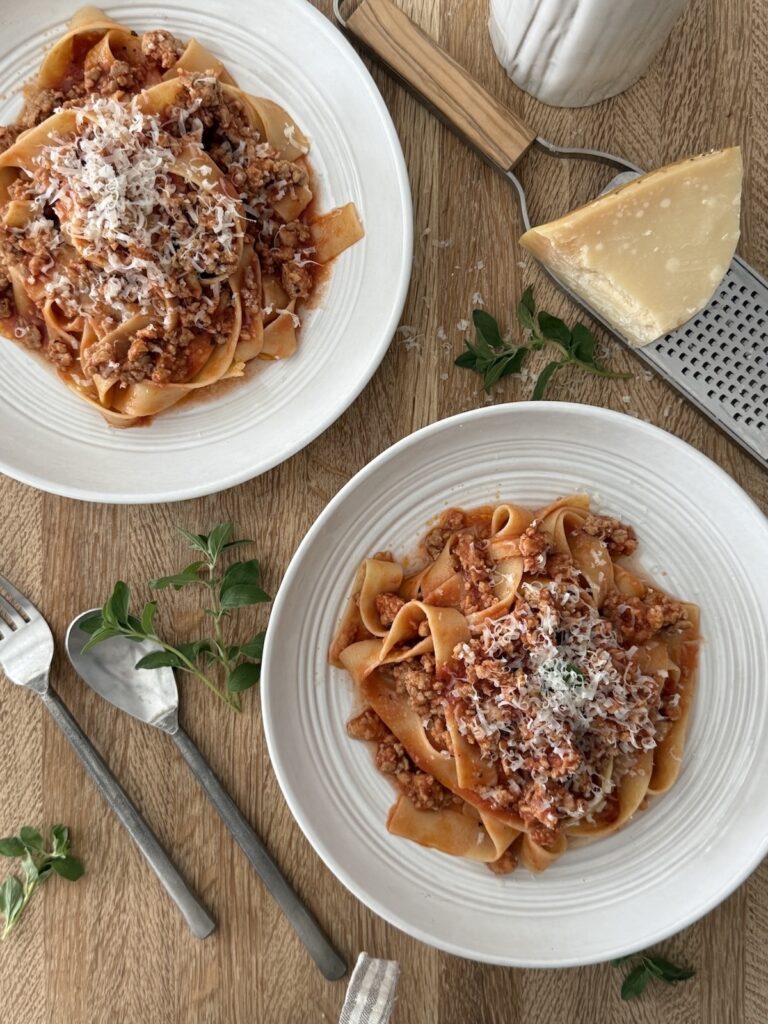 Chicken Bolognese served with pappardelle pasta and freshly grated Parmesan cheese.