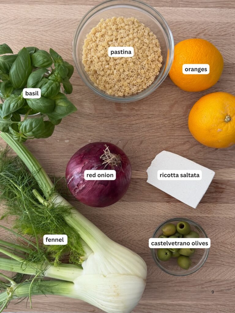 Ingredients for pastina salad including fennel, oranges, red onion, basil, ricotta salata, and Castelvetrano olives